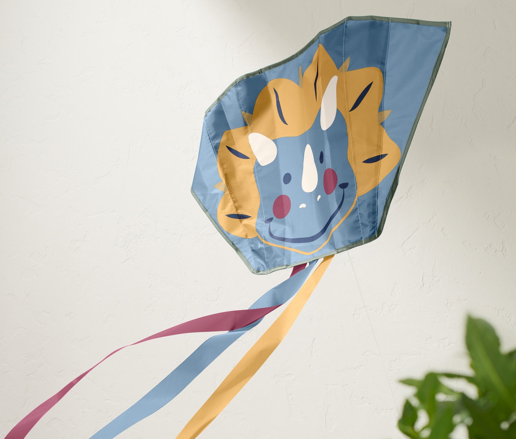 Dinozor yüzü ve renkli kurdeleleri olan mavi cep uçurtması.