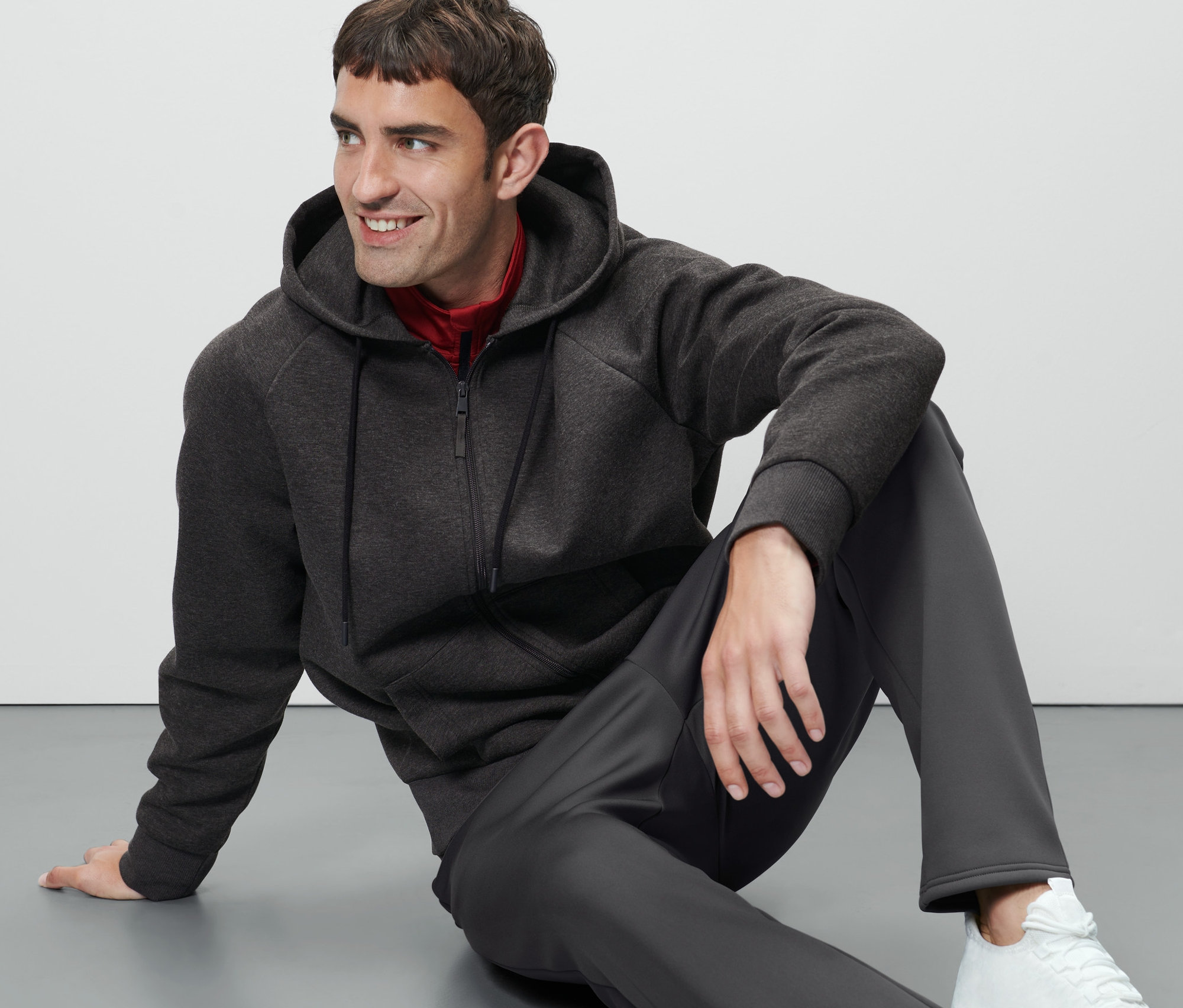 Adam yerde oturuyor ve Fonksiyonel Kapüşonlu Ceket giyiyor.