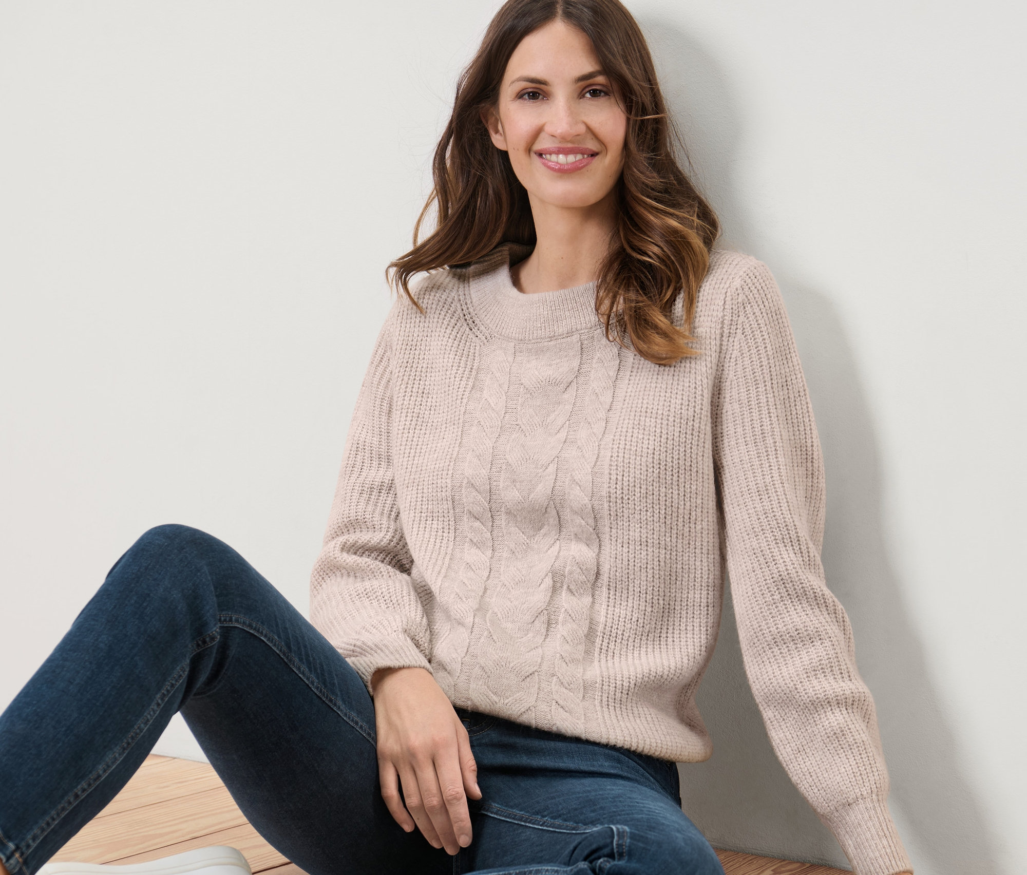 Kadın yerde oturuyor ve Kalın Örgü Kazak giyiyor.