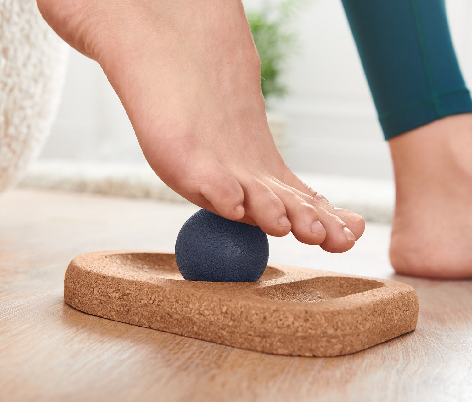 Ayak, mantar taban üzerinde mavi masaj topu bulunan Ayak Masajı Seti üzerinde duruyor.