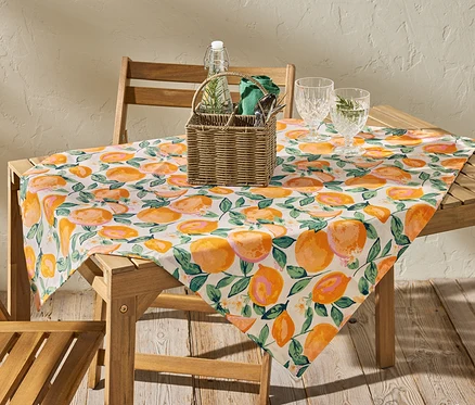 Ahşap bir masanın üzerinde, yaklaşık 90 x 90 cm boyutlarında, turuncu renkli, silinebilir bir masa örtüsü bulunmaktadır.