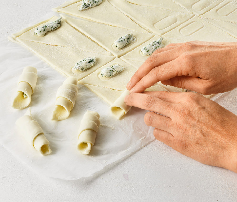 Eller kruvasanları Kruvasan Rulosu ile sarıyor.