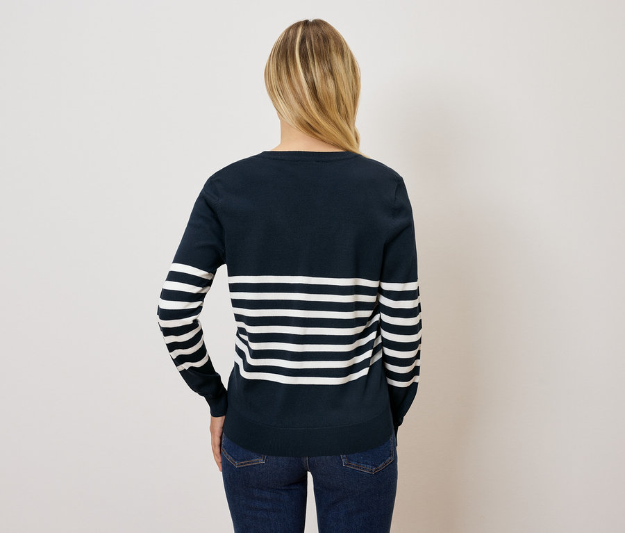 Arkadan, lacivert beyaz çizgili bir kazak ve kot pantolon giyen sarı saçlı bir kadın görülüyor.