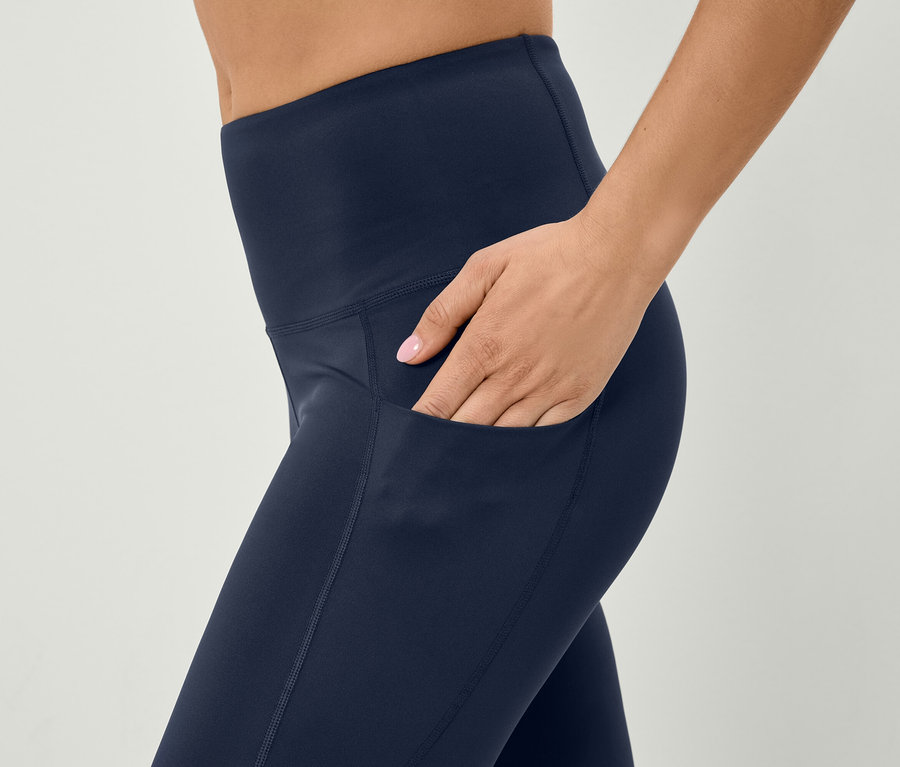 Kadın, lacivert taytın cebine elini sokuyor.