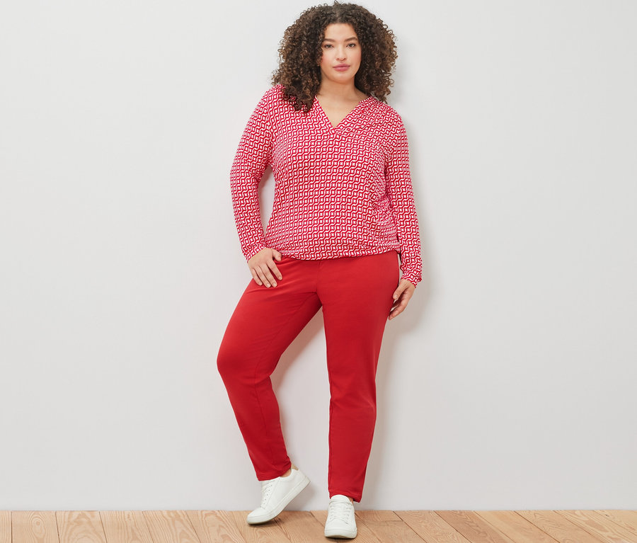 Kadın kırmızı baskılı bluz ve kırmızı jogger pantolonla poz veriyor.