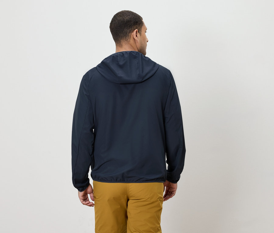 Kapüşonlu lacivert bir ceket ve sarı pantolon giyen bir adamın arkadan görünüşü.