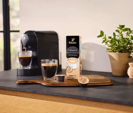 Kahve makinesi, bir bardak kahveyi Cafissimo Decaffeinato kapsül paketinin yanına döküyor.