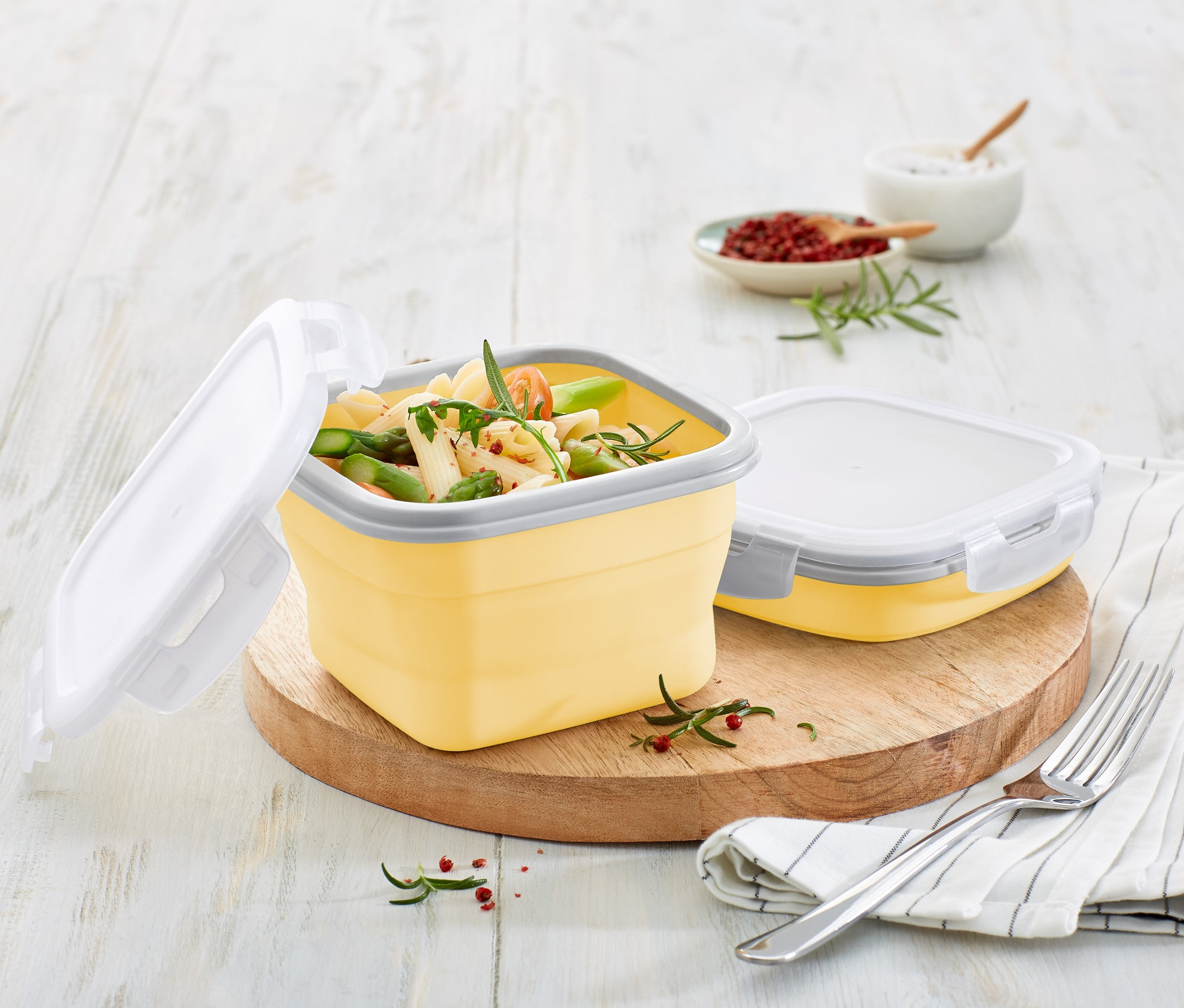 Açık sarı katlanabilir saklama kutusunda yemek ve kesme tahtası üzerinde kapalı bir kutu.