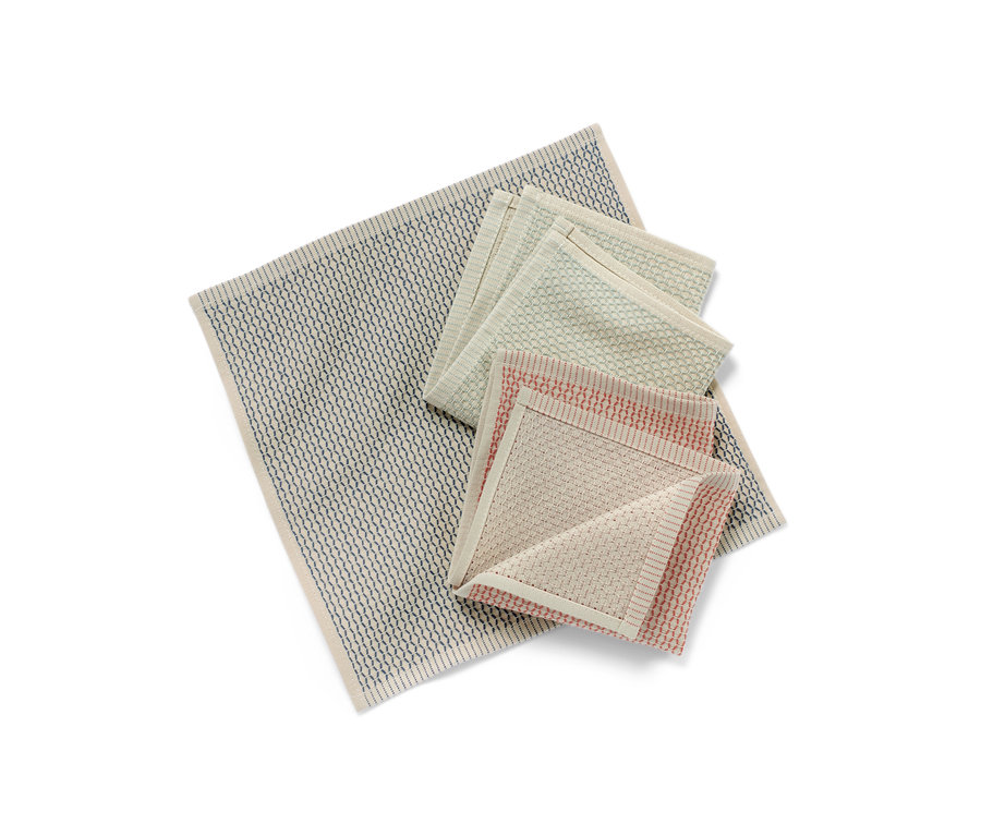 Üç adet bulaşık bezi katlanmış şekilde üst üste ve yan yana duruyor. Bir tanesi beyaz desenli mavi, diğer ikisi yeşil ve kırmızı.