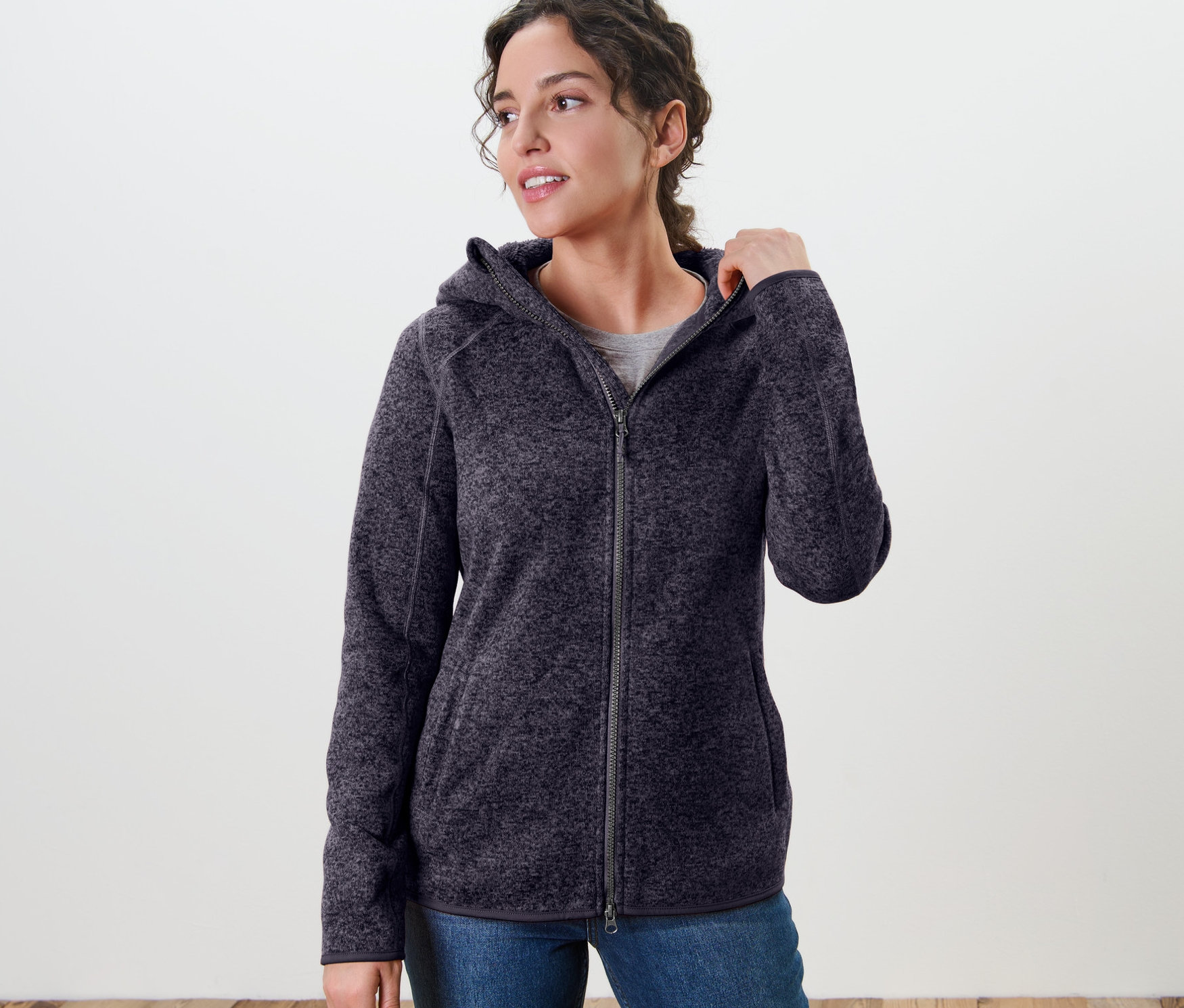Kadın kırçıllı lacivert kapüşonlu örgü polar ceket giyiyor.