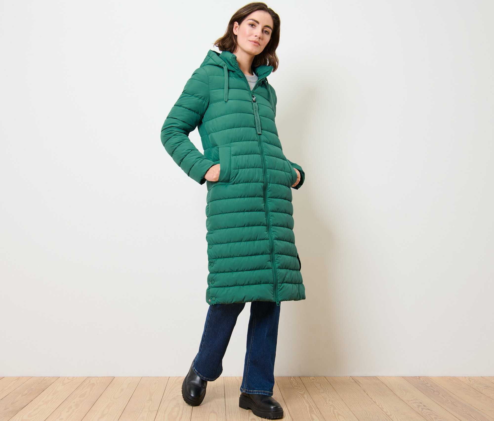 Kadın kapüşonlu kapitone bir uzun manto ile poz veriyor.