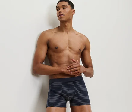 Duvara yaslanmış bir adam, 2'li Slip Boxer setinden birini giyiyor.