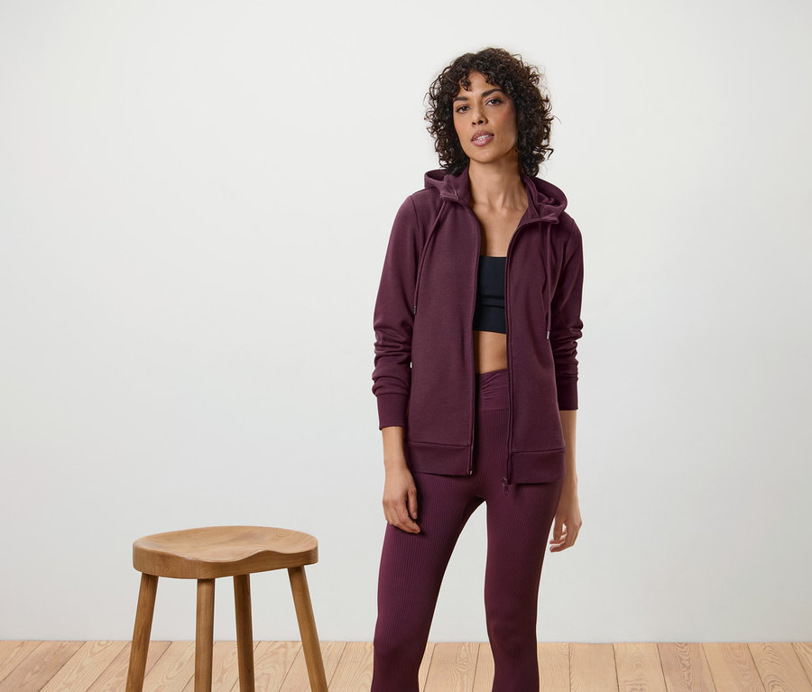 Kadın bir Sweat Ceket, tayt ve sporcu sütyeni giyiyor.