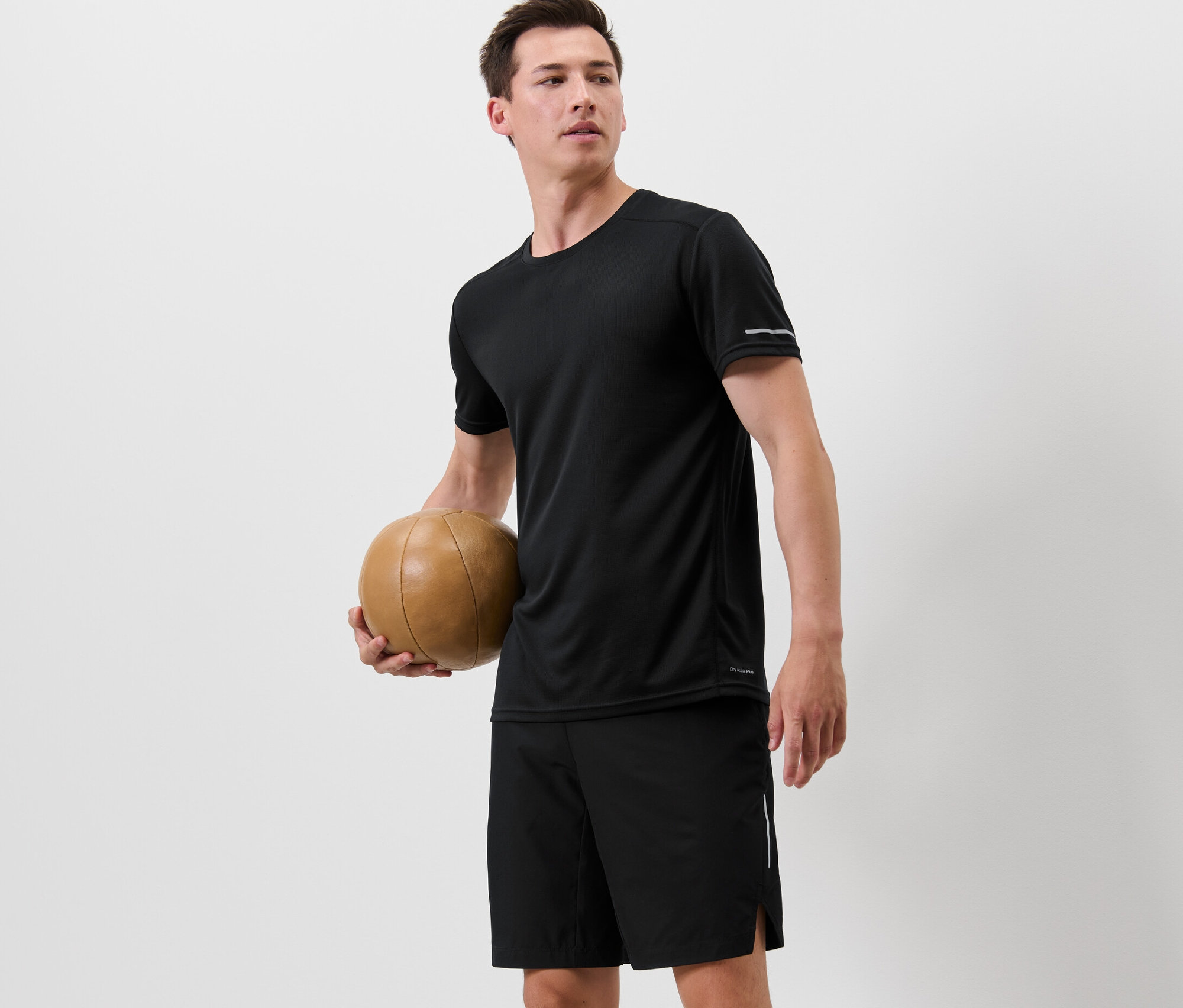 Adam basketbol topu tutuyor ve siyah fonksiyonel tişört giyiyor.