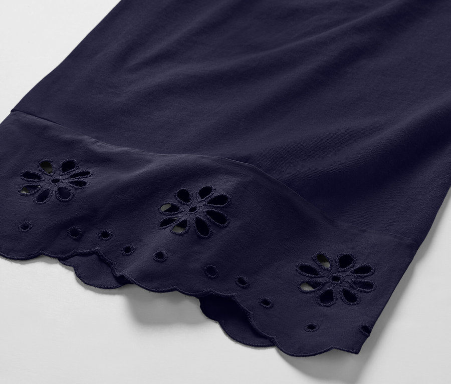 Etek ucunda çiçek nakışları olan lacivert renkli bir culotte pantolonun yakın çekimi.