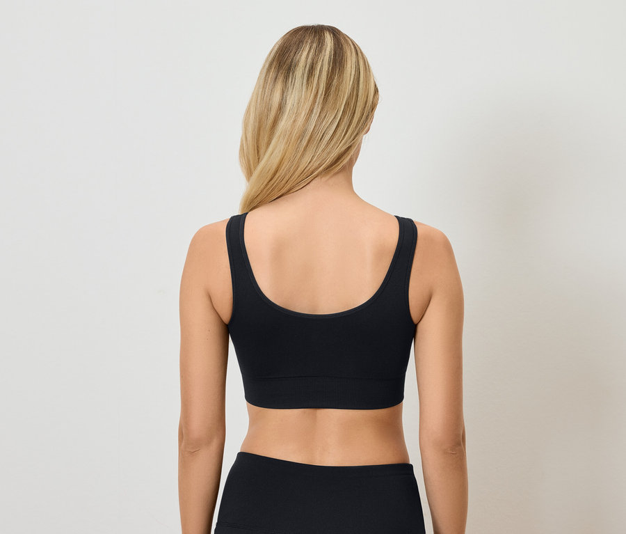 Siyah sporcu sütyeni ve pantolonu giyen sarışın bir kadının arka görünümü.