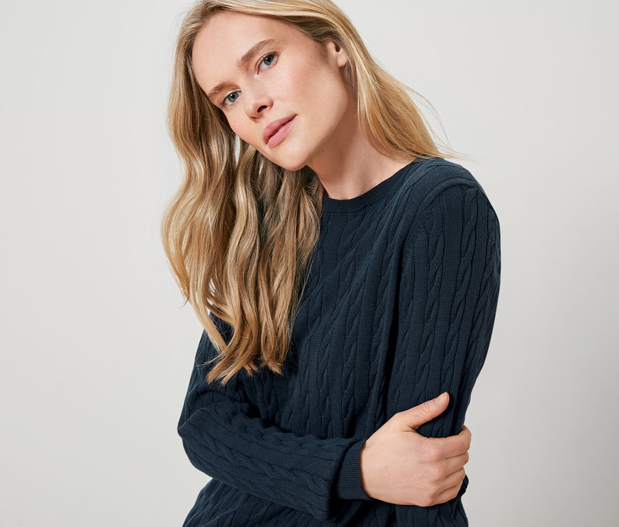 Sarışın bir kadın lacivert örgü kazak giyiyor.