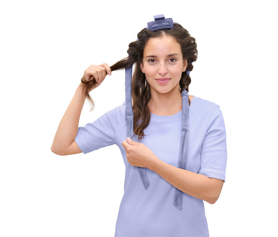 Kadın mavi bir saç bigudisi ile saçını sarıyor.