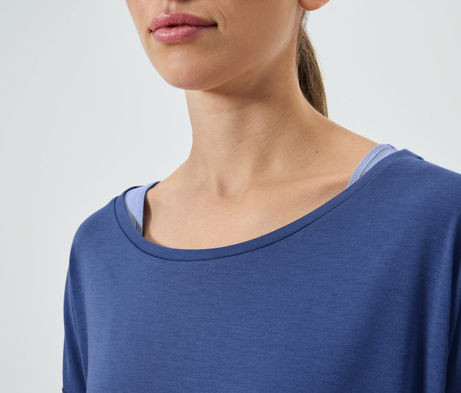 Kahverengi saçlı, mavi kısa kollu tişört ve mavi atlet giyen bir kadının yakın çekimi.