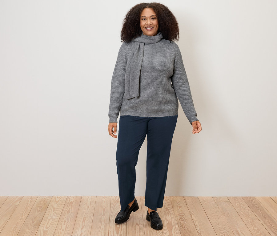 Kadın gri bir kazak ve lacivert Konforlu Jersey Pantolon giyiyor.