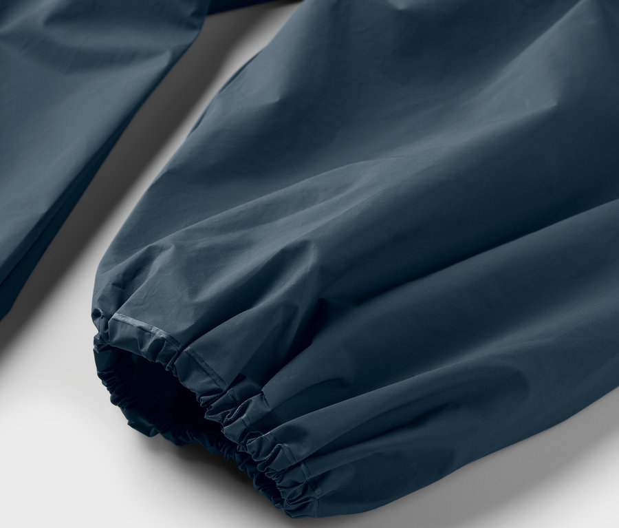 Mavi bir yağmurluk pançosunun kolunun yakın çekim görüntüsü.