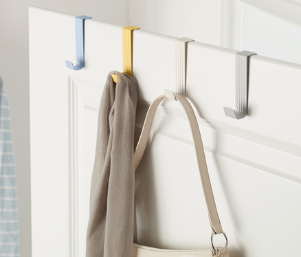 Bir kapıda farklı renklerde 4 adet kapı askısı asılıdır, üzerinde bir eşarp ve bir el çantası bulunmaktadır.