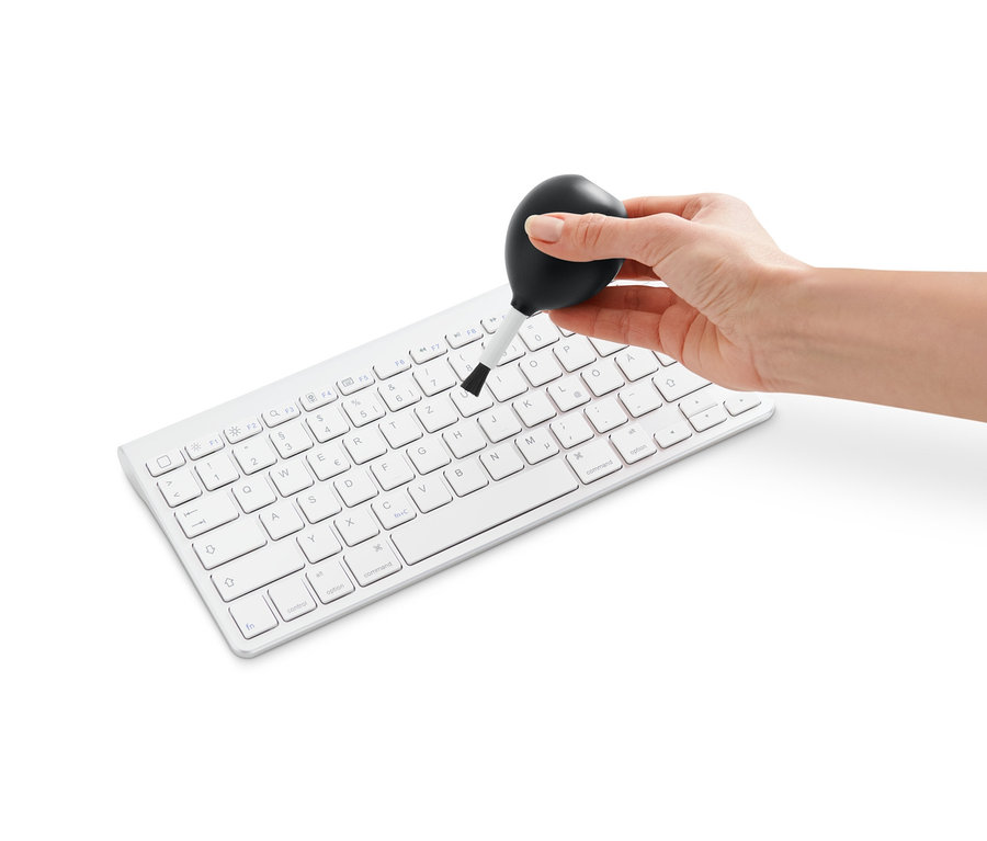 Bir el, beyaz bir klavyeyi 2'si 1 Arada Üfleyen Fırça ile temizliyor.