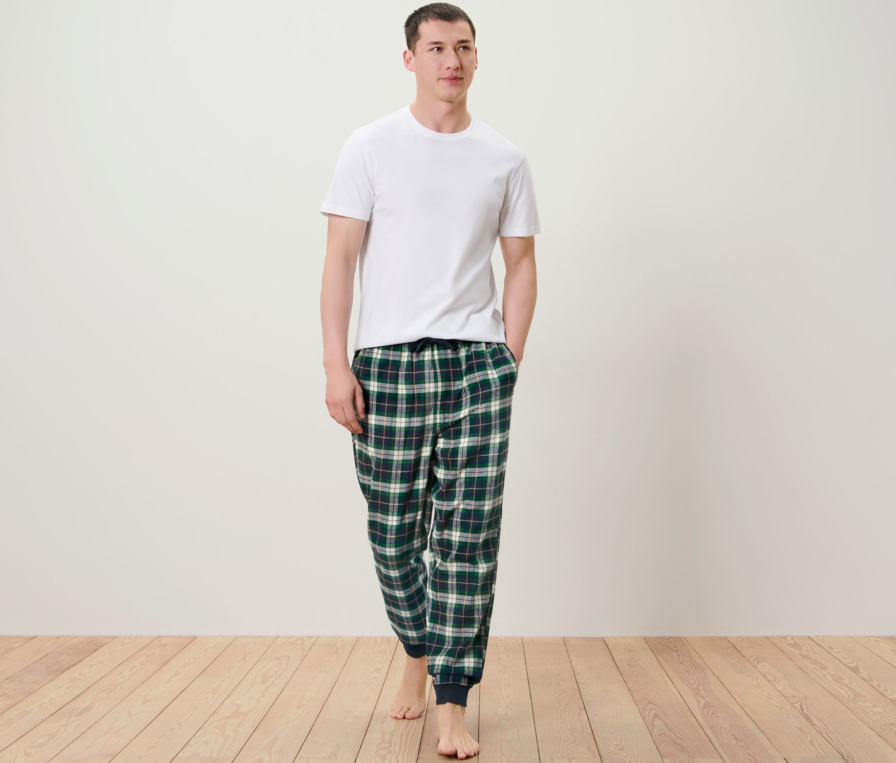 Adam yürüyor ve rahat flanel pantolon giyiyor.