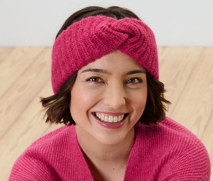 Gülümseyen bir kadın pembe bir saç bandı takıyor.