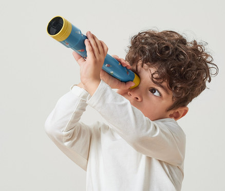 Oğlan oyuncak durbun ile bakıyor.