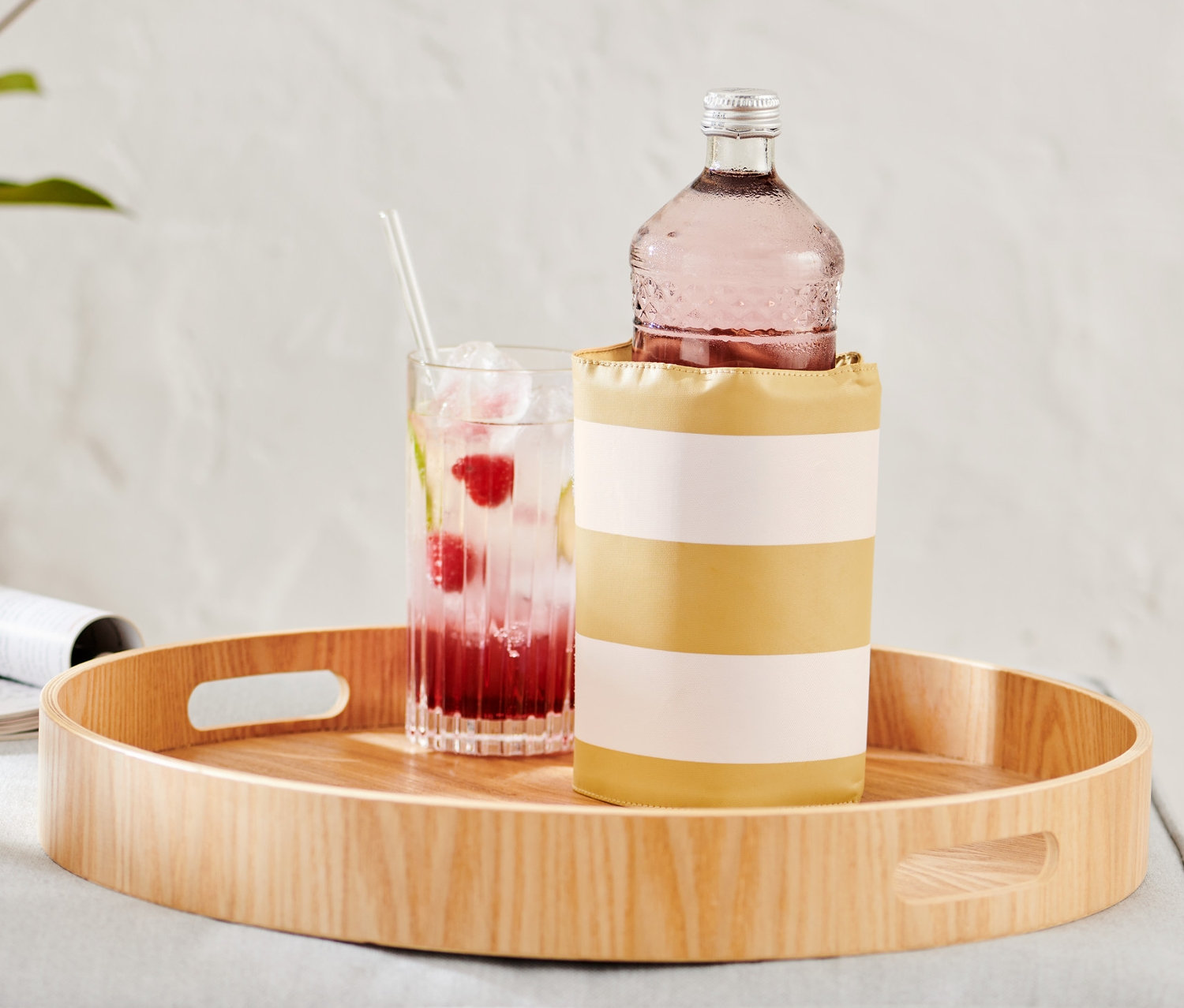 Ahşap bir tepside bir bardak içecek ve bir şişe ile birlikte Şişe Soğutucu Kılıf bulunmaktadır.