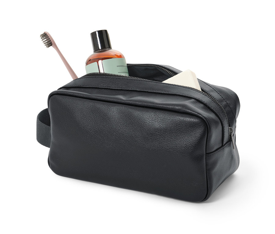 İçinde kahverengi bir şişe, diş fırçası ve sabun bulunan siyah bir kişisel bakım çantası.