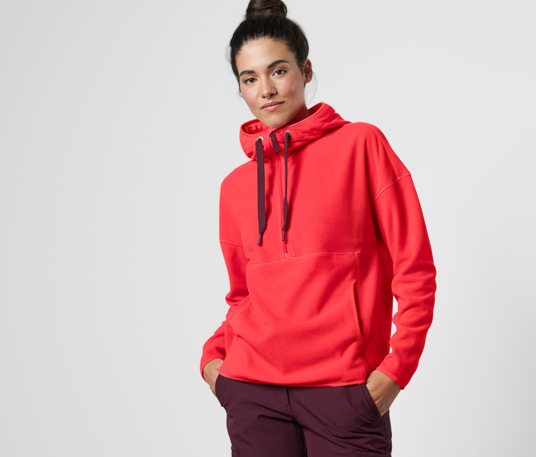 Kadın kırmızı kapüşonlu polar kazak ve mor pantolonla poz veriyor