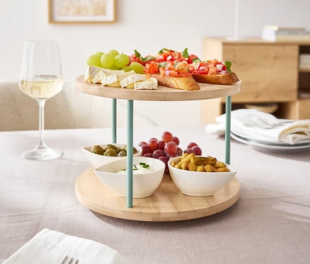 Bruschetta, peynir ve meyve gibi atıştırmalıkların bulunduğu döner bir etajer masa üzerinde duruyor.