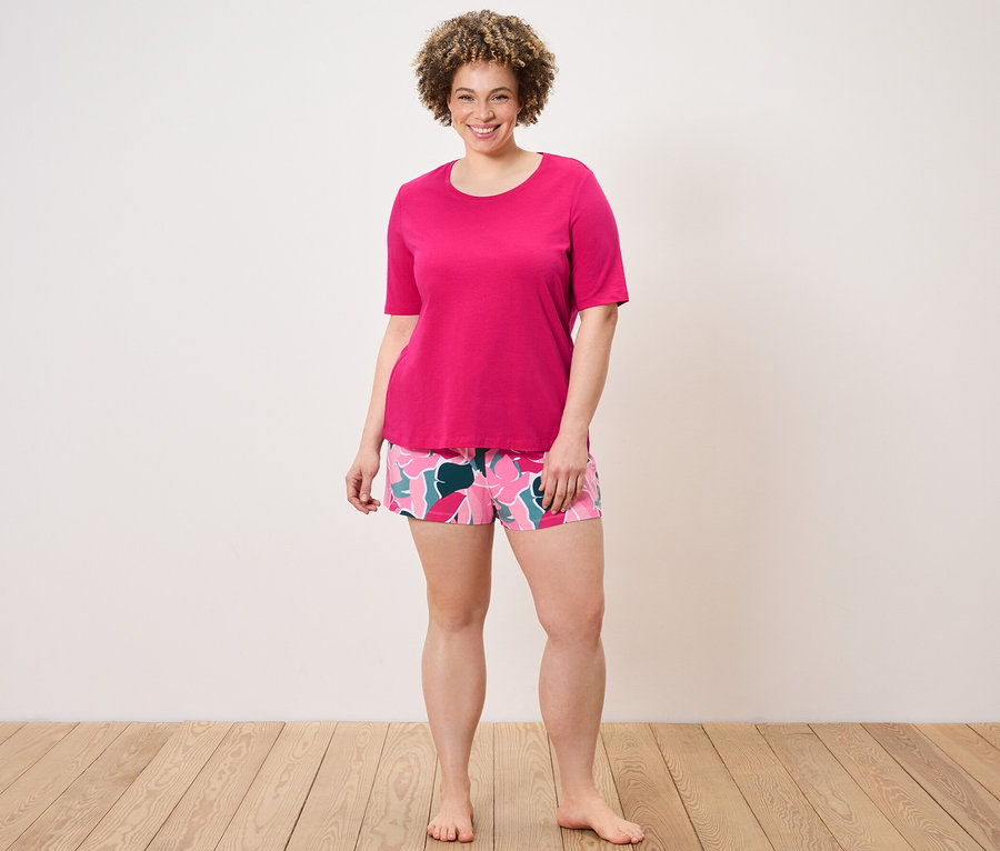 Kadın şortlu pijama takımı giyiyor.