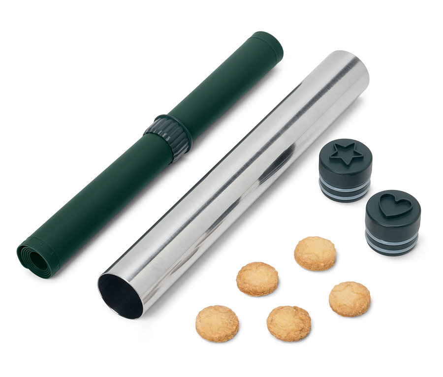 Yeşil bir oklava matı ve yıldız ve kalp şeklinde kurabiye kesicileri ve kurabiyeleri olan gümüş bir oklava.