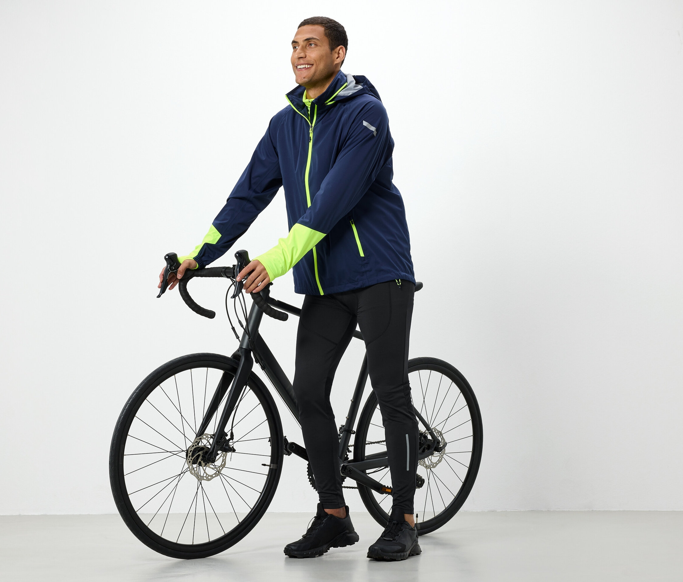 Ceketli adam siyah bir bisiklet tutuyor.