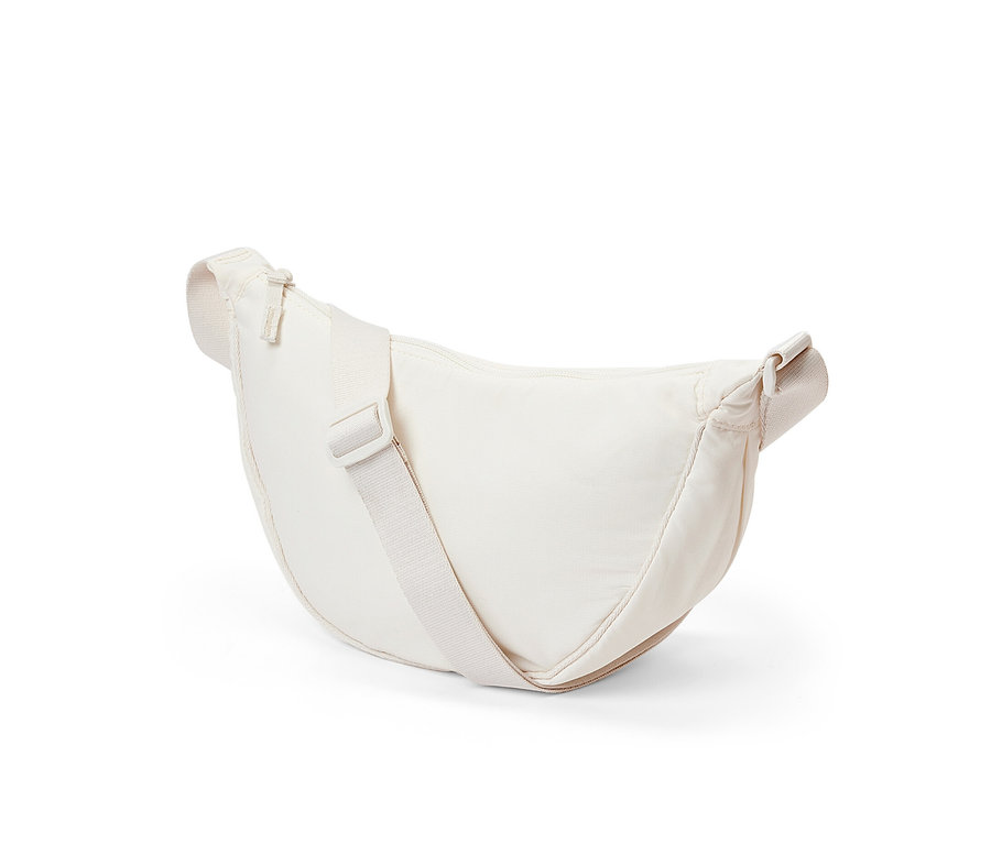 Krem rengi omuz çantası beyaz bir arka plan üzerinde duruyor.