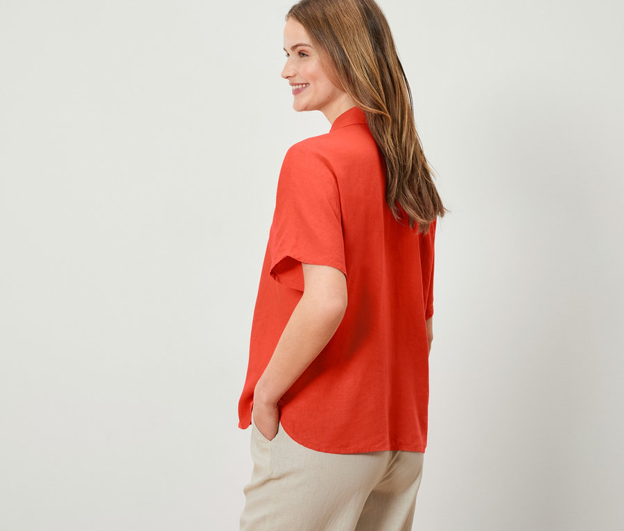 Kadın turuncu renkli keten bluzla poz veriyor.