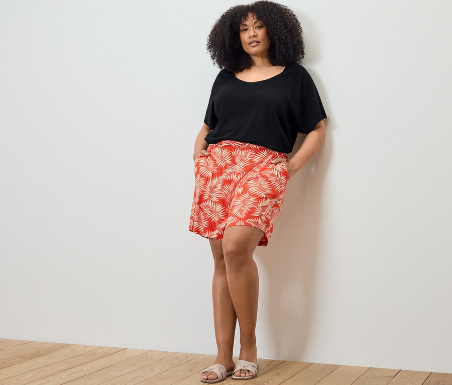 Kadın, keten karışımlı tişört ve baskılı jarse şortla poz veriyor.