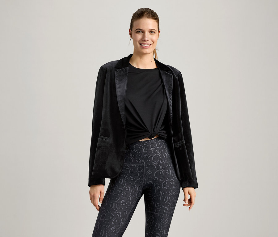 Kadın siyah bir spor tişörtü ve siyah bir blazer ceket giyiyor.