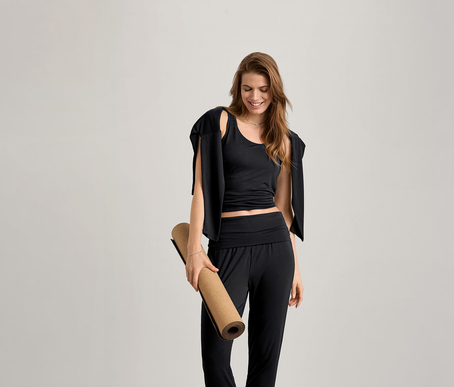 Kadın yoga matı tutuyor ve siyah 2'si 1 Arada Kadın Spor Tişörtü giyiyor.