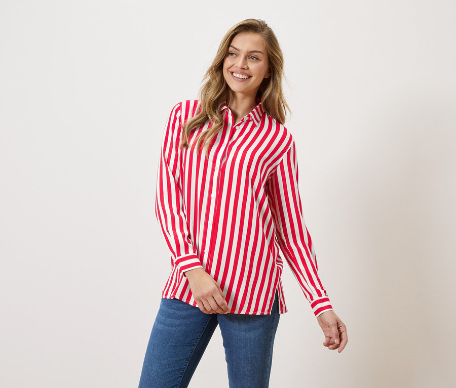Kadın, kırmızı beyaz çizgili bir gömlek ve kot pantolon giyiyor.