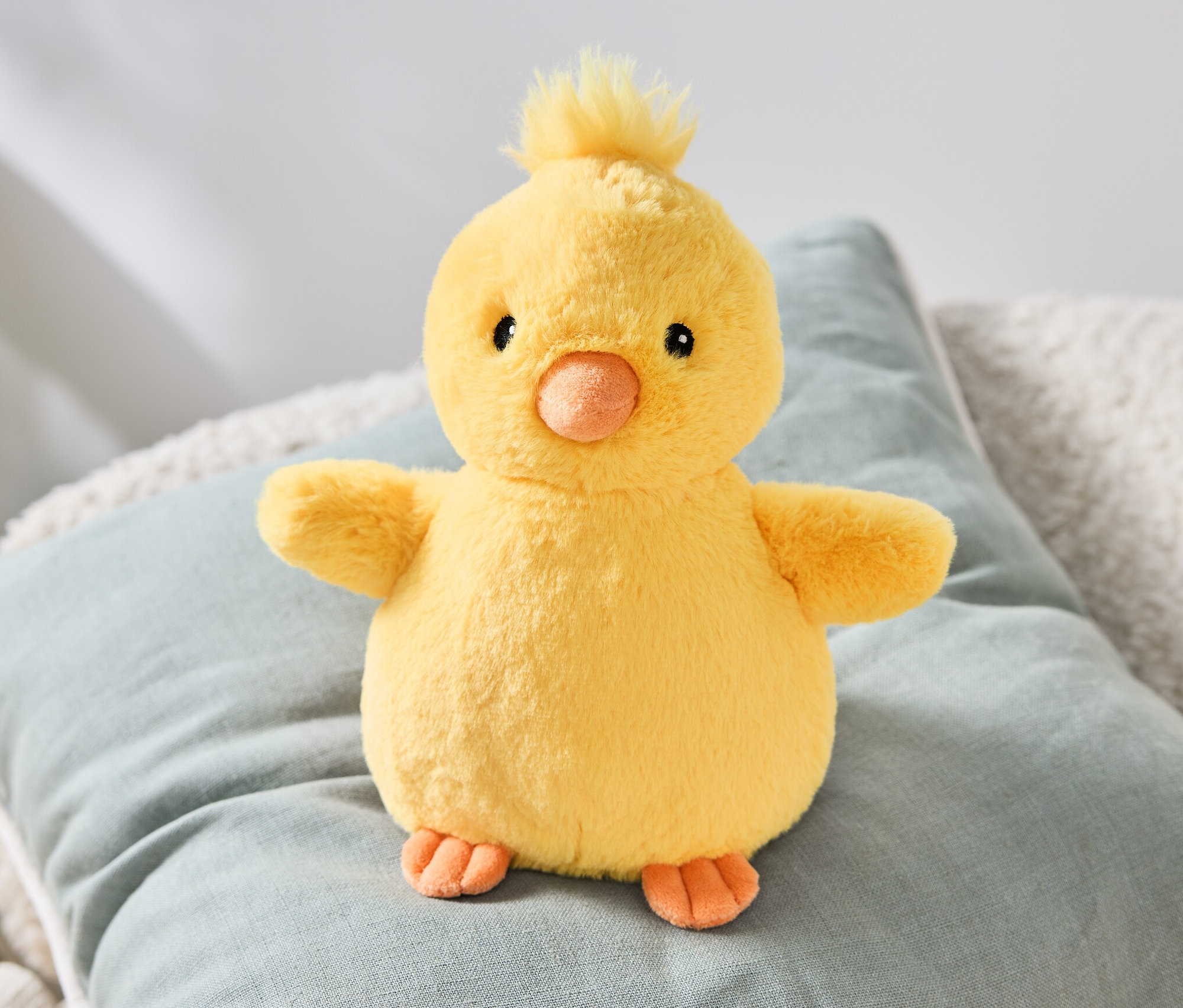 Pelüş civciv bir yastığın üzerinde oturuyor.