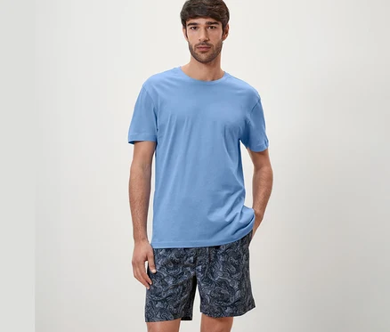 Adam mavi şortlu pijama takımı giyiyor.