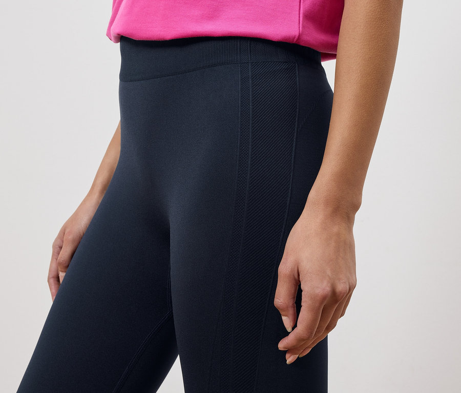 Kadın tayt ve pembe bir üst giyiyor.