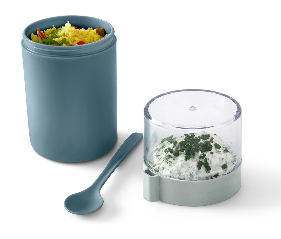 İçindekilerle birlikte yeşil bir Taşınabilir Yoğurt Kabı, yanında bir kaşık ve bitkisel kremalı peynir bulunan bir kap.