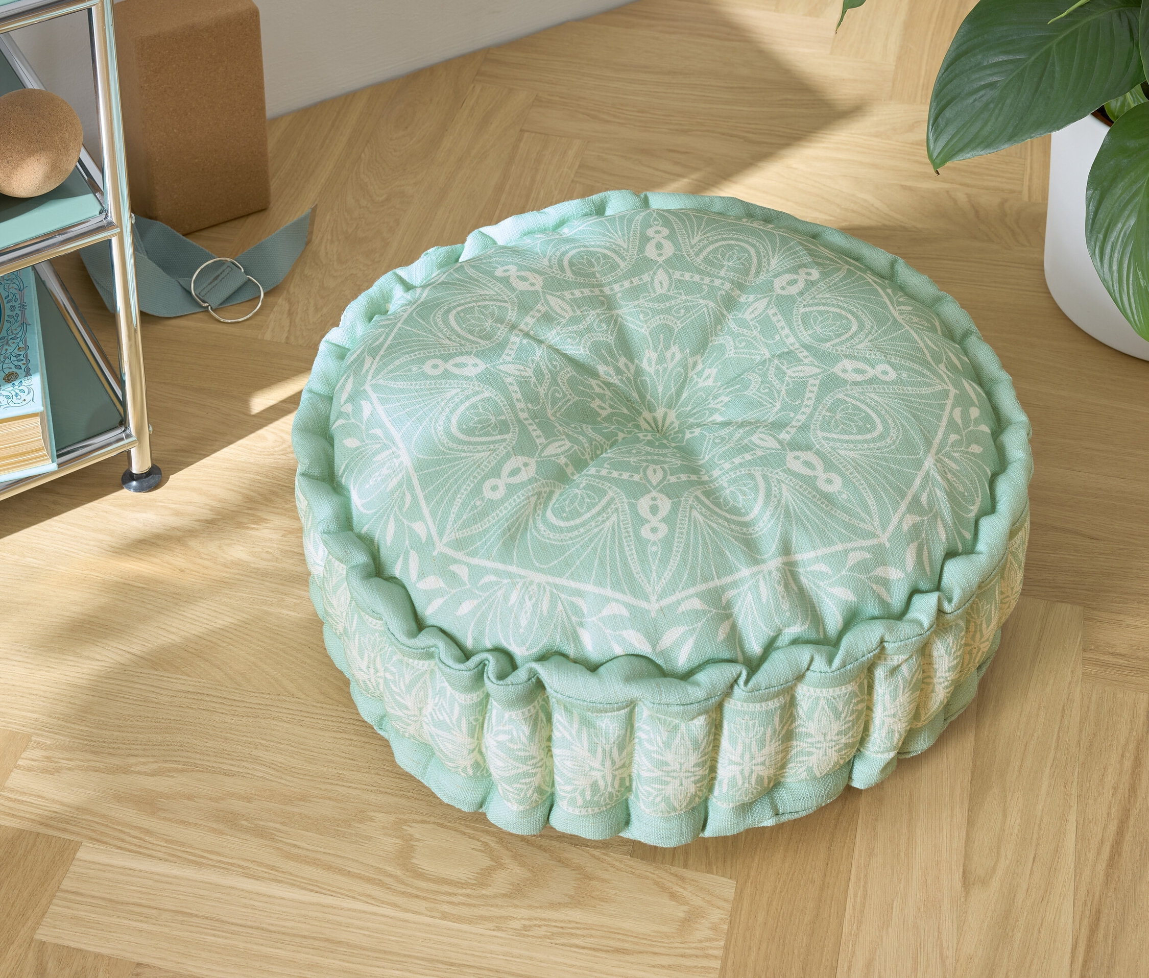 Ahşap zeminde beyaz desenli yeşil bir minder.