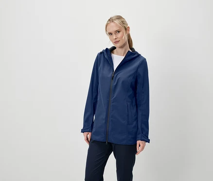 Kadın kapüşonlu lacivert softshell ceket ve lacivert pantolonla poz veriyor.