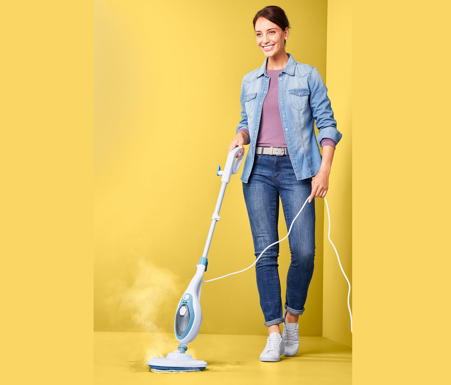 Sarı bir arka plan üzerinde çok fonksiyonlu buharlı süpürge kullanan kadın.